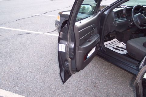 2001 Ford Crown Victoria - The interior of a dark 2001 Ford Crown Victoria is visible with the driver's side door ajar.
