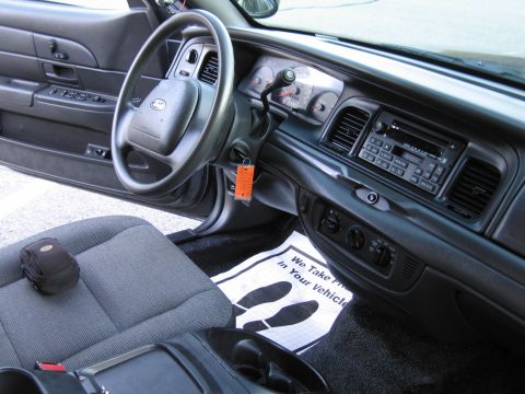 2001 Ford Crown Victoria - The interior of a 2001 Ford Crown Victoria, the driver's side seat, steering wheel, and dashboard with a radio.