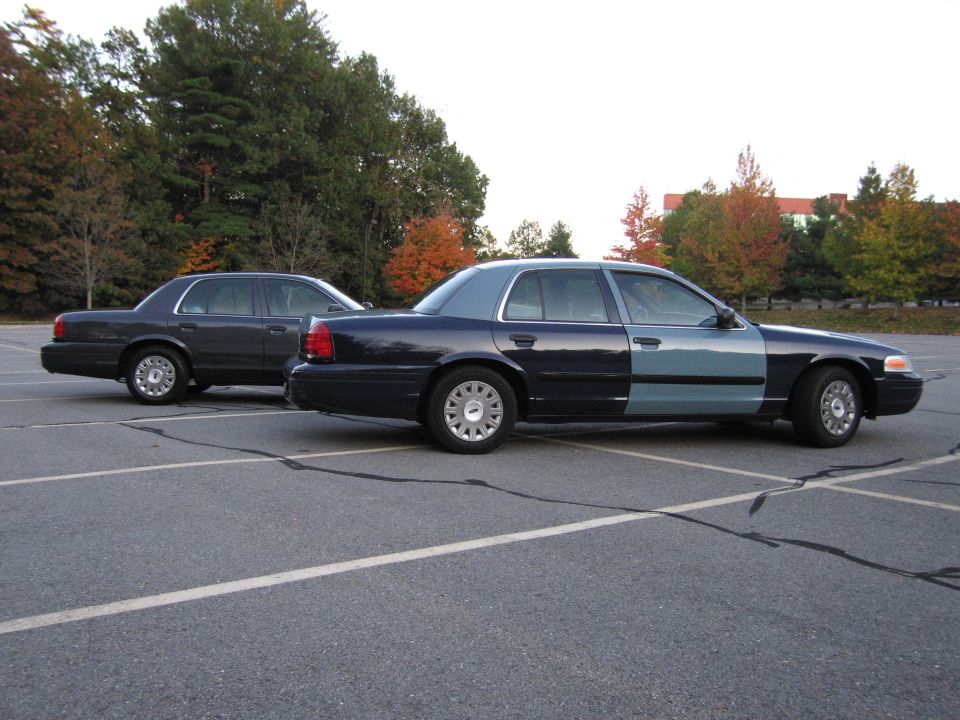 Two Ford Crown Victoria sedans parked, side and rear views