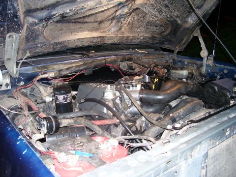1991 Ford Bronco - The open hood reveals a detailed view of the engine bay of a blue Ford Bronco. Various hoses, wiring, and engine components are visible, al…