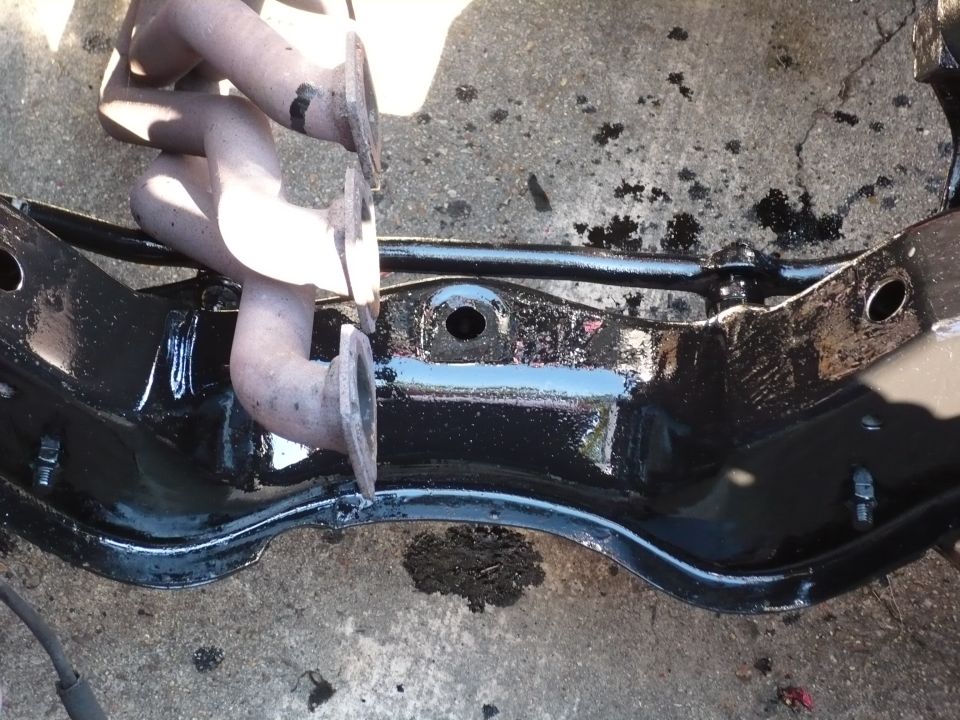 Black painted engine subframe with exhaust manifold pipes.