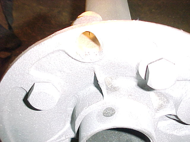 Close-up of a white painted vehicle part with hexagonal bolts and a circular opening.