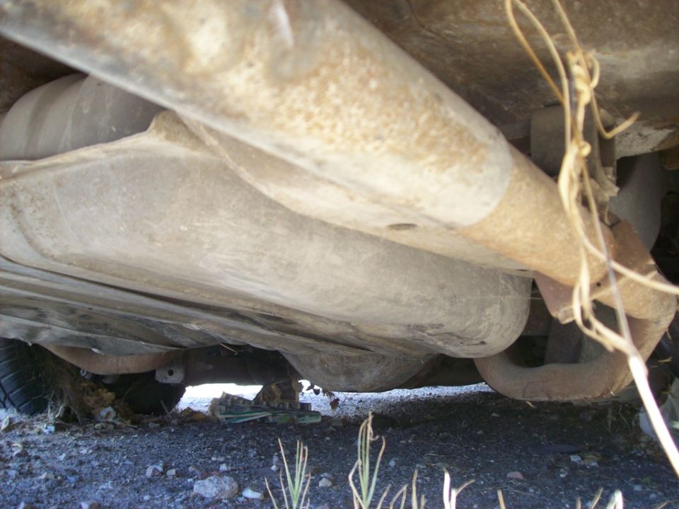 Underside of a vehicle showing fuel tank and exhaust system.