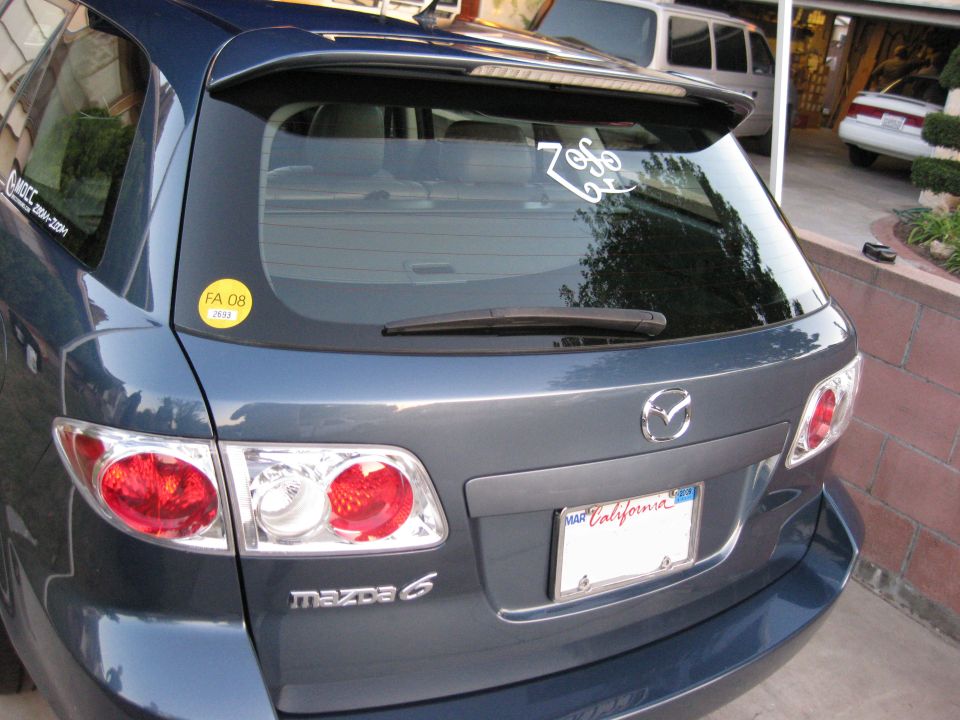 Rear view of a dark blue Mazda 6 hatchback with a spoiler and a California license plate.