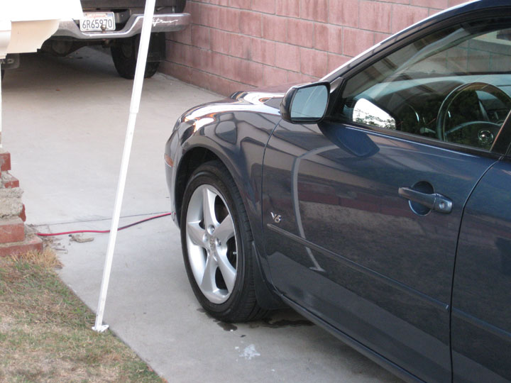 Side view of a dark blue car, showing the front wheel and door.