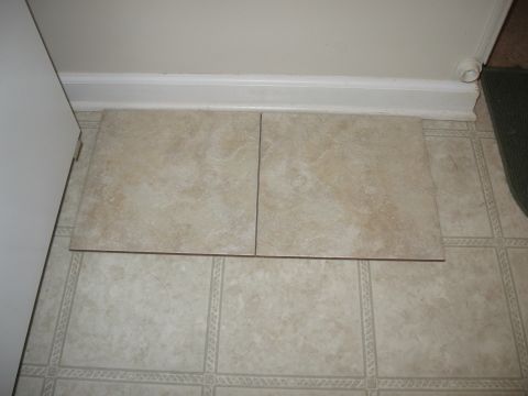 1995 Ford F-150 - Two beige-colored floor tiles are placed on top of a patterned linoleum floor near a white baseboard and a white door frame.