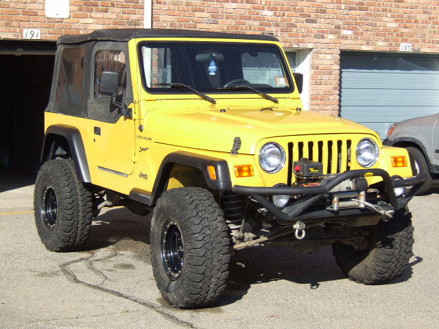 Yellow 2002 Jeep TJ Wrangler with off-road tires and winch.