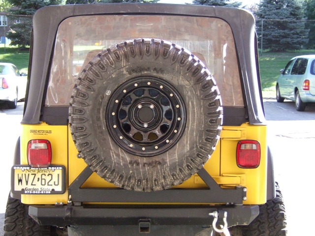 Rear view of a yellow 2002 Jeep TJ with a spare tire and NJ license plate.