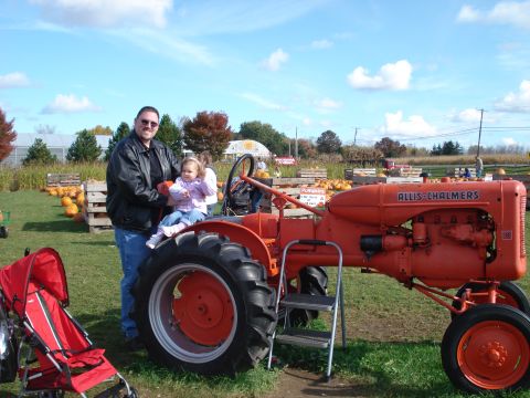 2000 Ford Crown Victoria - A man stands next to an orange Allis-Chalmers tractor at a pumpkin patch, holding a young girl on his lap. A red stroller is parked to the…