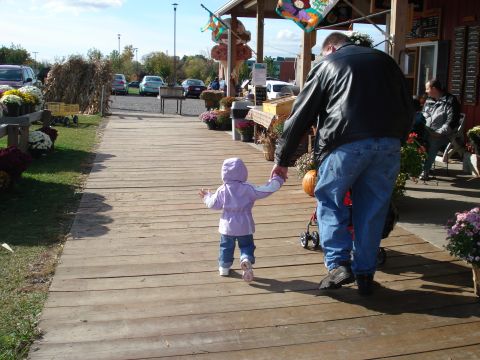 2000 Ford Crown Victoria - A man in a black leather jacket and blue jeans holds the hand of a small child in a purple hooded jacket as they walk down a wooden boardwa…