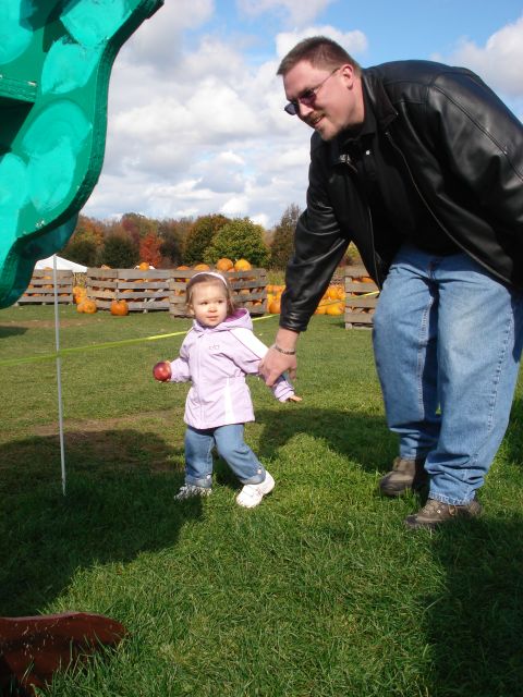 2000 Ford Crown Victoria - A man and a young child are at a pumpkin patch with wooden crates filled with pumpkins in the background.