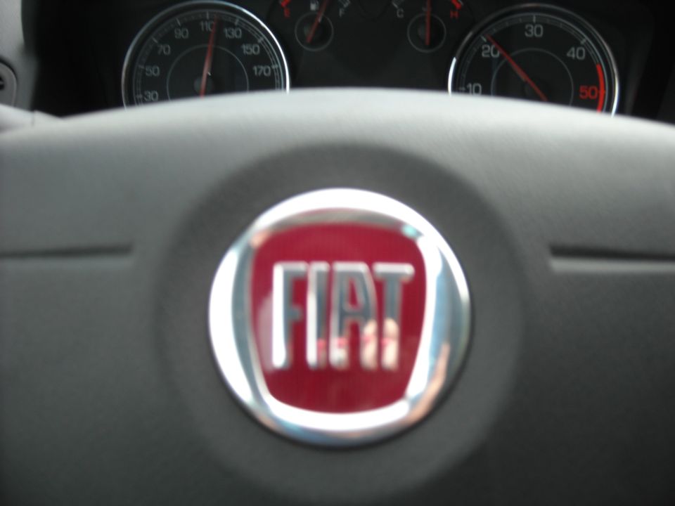 Fiat emblem on a steering wheel with dashboard gauges visible