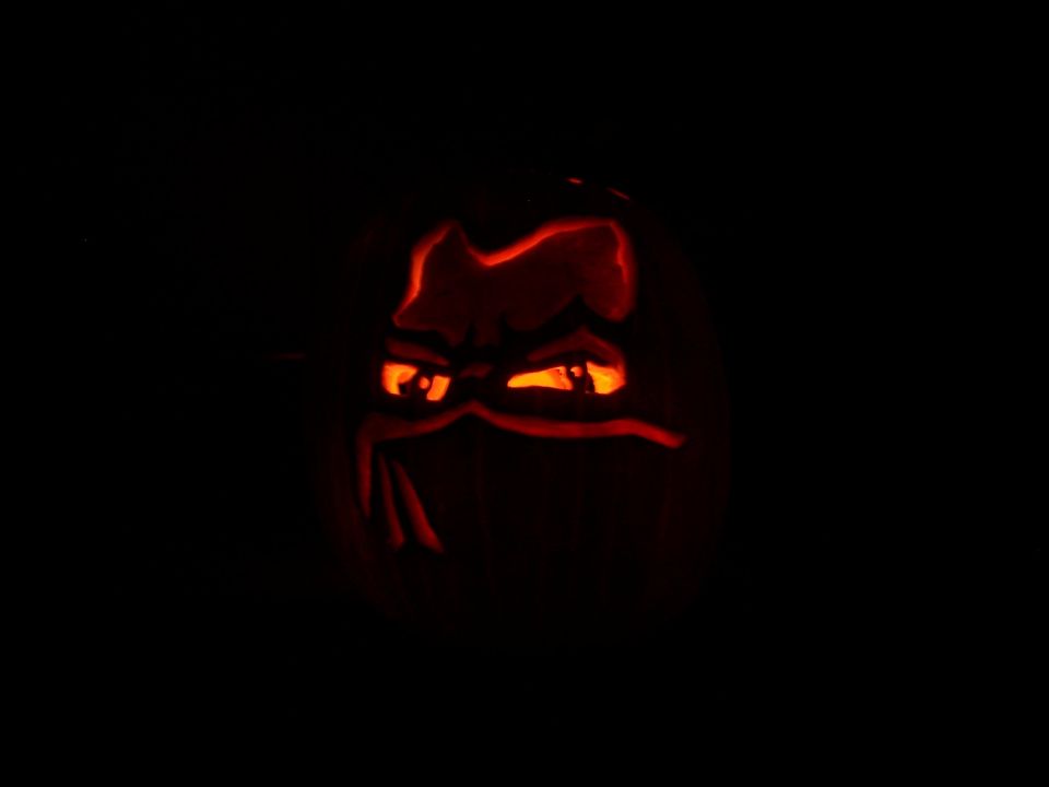Jack-o'-lantern with glowing orange eyes and mouth carved into a dark background