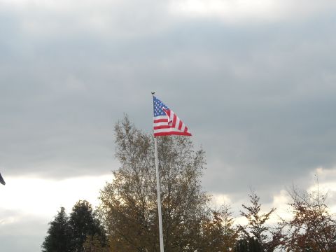 1979 Ford F-150 - An American flag flies against a backdrop of overcast skies and autumn foliage.