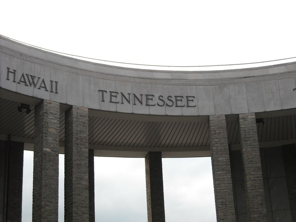 Stone monument with 'HAWAII' and 'TENNESSEE' carved into it, supported by stone pillars