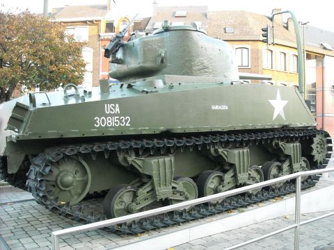 1979 Ford F-150 - A military tank with tracks and a mounted machine gun is displayed outdoors.