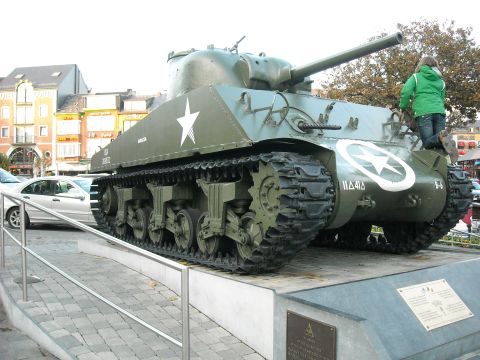1979 Ford F-150 - A military tank is on display in a town square, with a person on top.