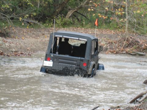 1991 Jeep Wrangler - A black 1991 Jeep Wrangler navigates a shallow water crossing on an off-road trail.