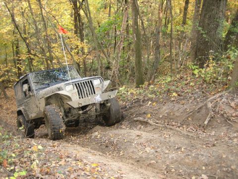 1991 Jeep Wrangler - 1991 Jeep Wrangler navigating a muddy, wooded trail during the fall season.