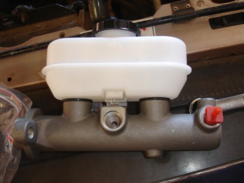 1992 Ford F-350 - A new master cylinder assembly, a white plastic reservoir and a metal body, is shown in this close-up view.