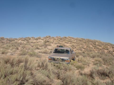 1992 Ford F-350 - A tan 1992 Ford F-350 navigates a dusty, brush-covered hillside under a clear blue sky.
