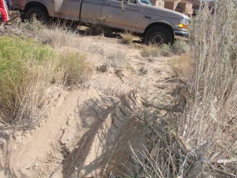 1992 Ford F-350 - A tan 1992 Ford F-350 truck is stuck in a sandy, off-road environment.