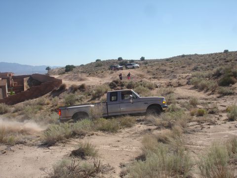 1992 Ford F-350 - A 1992 Ford F-350 kicks up dust as it navigates a dry, scrub-covered landscape with other vehicles visible in the background.