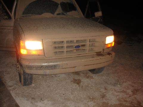 1992 Ford F-350 - Mud-covered 1992 Ford F-350 front end with headlights illuminated at night.