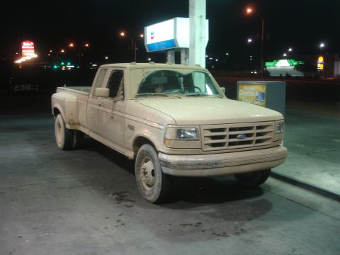1992 Ford F-350 - A dusty 1992 Ford F-350 dually truck is parked at a gas station under the night sky.