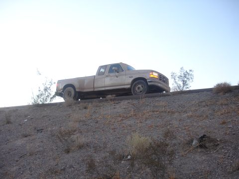 1992 Ford F-350 - This 1992 Ford F-350 pickup truck is seen from the side, parked on an incline under a clear sky.