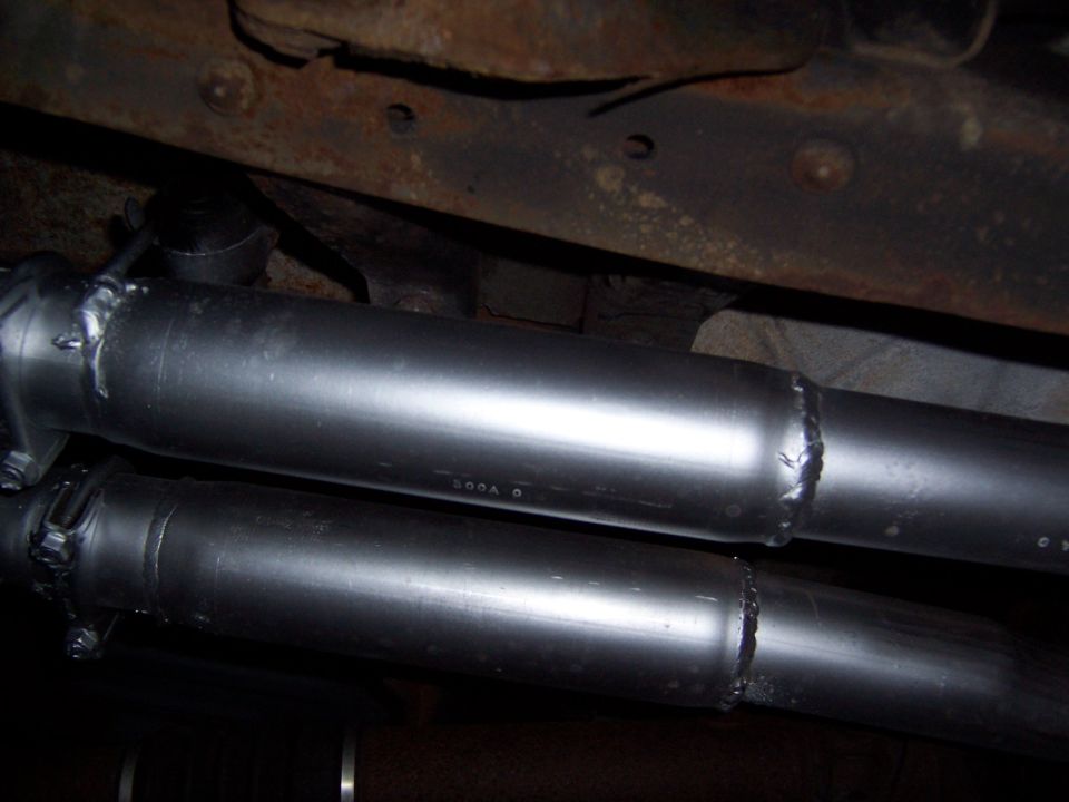 Underbody shot of dual exhaust pipes with welded muffler sections beneath a vehicle