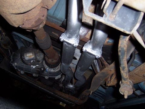 1995 Ford Bronco - The underside of a vehicle shows a newly installed dual exhaust system with prominent clamps and piping.