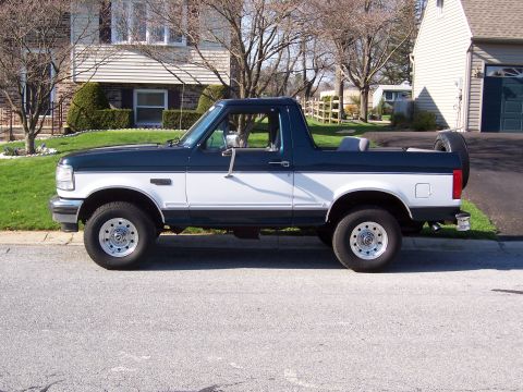 1995 Ford Bronco - This two-tone Ford Bronco is parked in front of a house and garage on a sunny day.