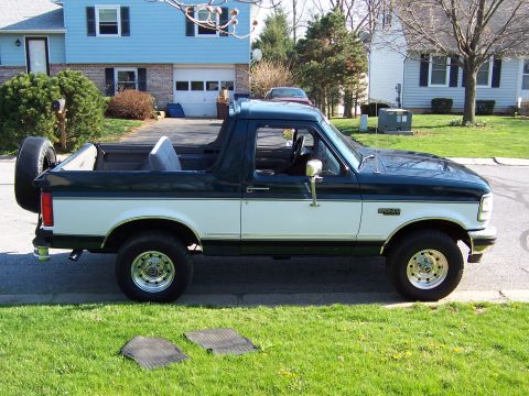1995 Ford Bronco - A two-tone green and white Ford Bronco is parked on a residential street.