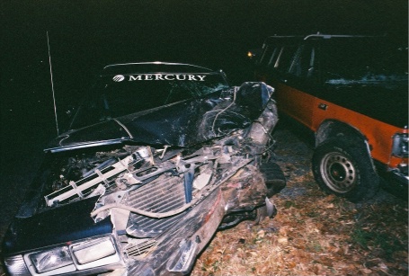 1988 Mercury Grand Marquis - A severely damaged 1988 Mercury Grand Marquis sits in front of an orange truck after an accident.