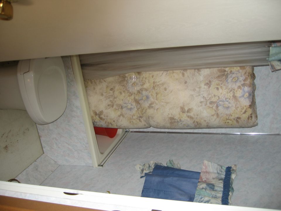 Interior view of a toilet and a floral patterned mattress in a recreational vehicle