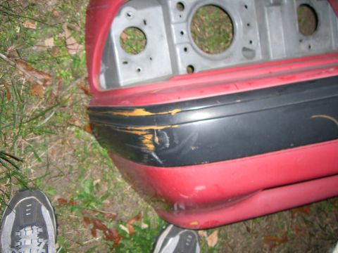 1988 Ford Bronco - This is a close-up of a damaged red car bumper with a black impact strip.