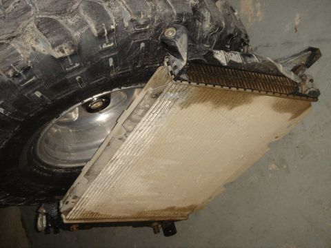1996 Ford Bronco - A removed radiator sits beside a large off-road tire, suggesting a repair or maintenance situation.