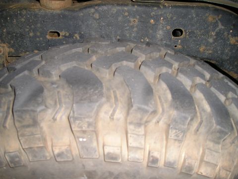 1989 Ford Bronco - A close-up view of a tire and vehicle frame shows off-road tread and some rust.