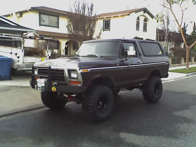Brown lifted Ford Bronco on large tires parked on a residential street