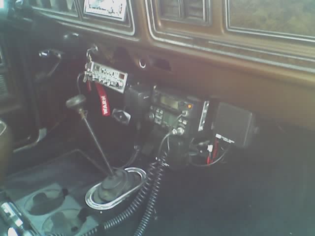 Bronco interior with floor shifter, red WARN strap, and CB/mobile radios mounted under the brown dash