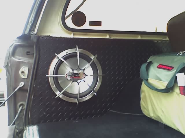 MTX subwoofer with chrome grille in black diamond-plate panel inside a vehicle cargo area