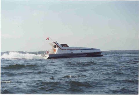 1978 Ford F-250 - A hydrofoil boat with a white hull and blue stripe cuts through the water, leaving a wake behind it.