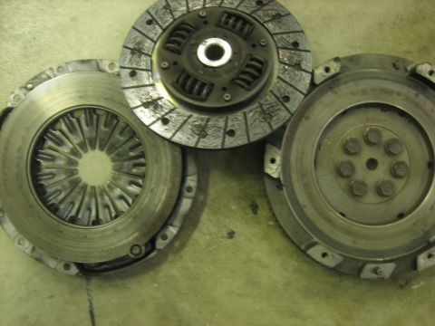1995 Mitsubishi Eclipse - A collection of automotive clutch and flywheel parts are laid out on a textured floor.
