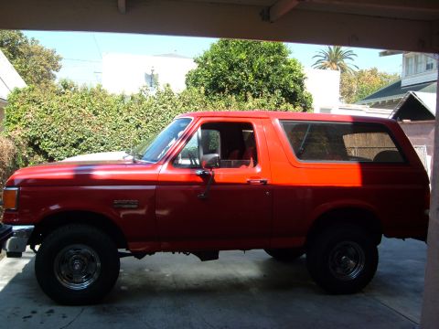 1988 Ford Bronco - A red 1988 Ford Bronco is parked in a garage, viewed from the side.