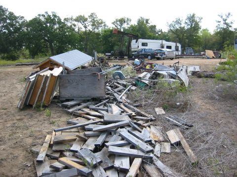 1996 Ford Bronco - A cluttered scene at a scrap yard includes an RV, a pickup truck, and a car amidst debris.
