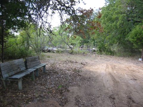 1996 Ford Bronco - A rustic scene two old wooden benches and a dirt path winding through a natural, wooded environment.