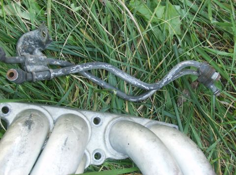 1995 Ford Probe - Close-up of an engine intake manifold and fuel lines resting on grass, with a "Supermotors.net" watermark visible.