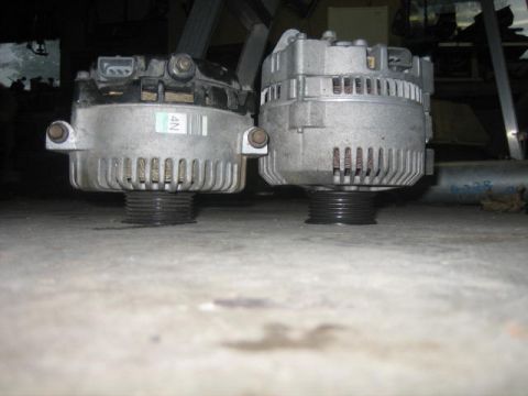 1996 Ford Thunderbird - Two automotive alternators are shown on a concrete floor, one with a visible part number sticker.