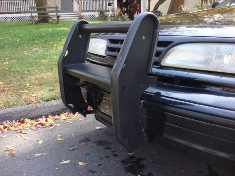 2003 Ford Crown Victoria - A black 2003 Ford Crown Victoria is parked on a street with fallen leaves on the ground.